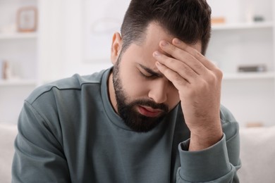 Photo of Man suffering from headache at home, closeup