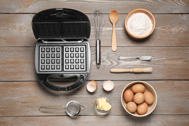 Photo of Flat lay composition with ingredients and Belgian waffle maker on wooden table