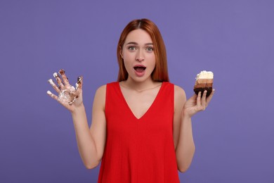 Photo of Emotional young woman with piece of tasty cake and dirty hand on purple background