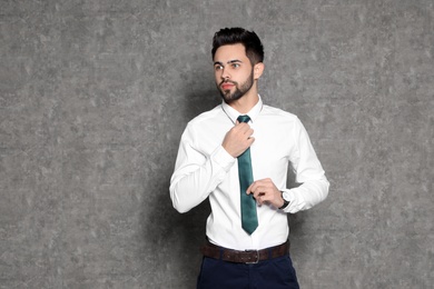 Photo of Portrait of businessman straightening tie on grey background