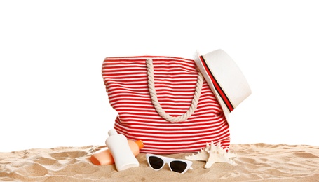 Photo of Stylish striped bag and beach accessories on sand against white background