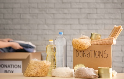 Photo of Donation box with food on table against brick wall