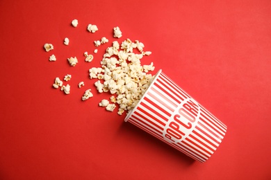 Photo of Paper cup with tasty fresh popcorn on color background, top view