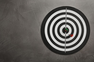 Photo of Dart board with color arrows on grey stone background, top view. Space for text