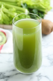 Photo of Glass with fresh celery juice on white marble table, closeup