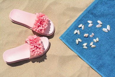 Photo of Towel, seashells and flip flops on sand, flat lay. Beach accessories