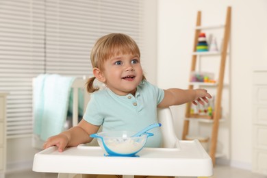 Photo of Cute little child eating tasty yogurt with spoon at home