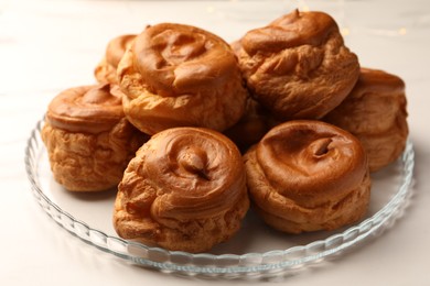 Photo of Delicious profiteroles on white table, closeup view