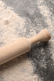 Photo of Scattered flour and rolling pin on grey textured table, top view