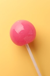 Photo of One tasty lollipop on yellow background, top view