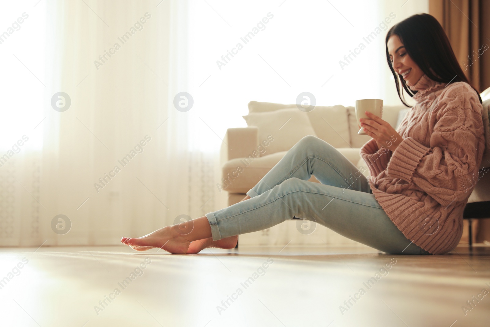 Photo of Woman sitting on warm floor in living room. Heating system