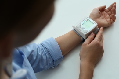 Photo of Woman checking blood pressure with sphygmomanometer at table, closeup. Cardiology concept