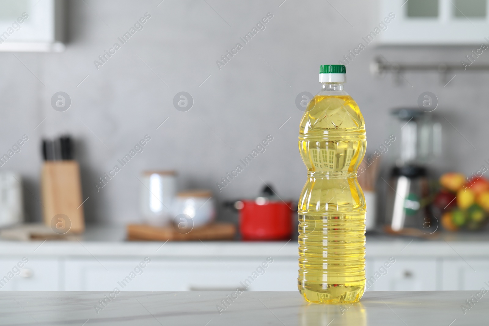 Bottle of cooking oil on white marble table in kitchen. Space for text Photo of Bottle of cooking oil on white marble table in kitchen. Space for text