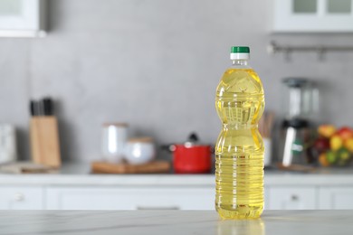 Photo of Bottle of cooking oil on white marble table in kitchen. Space for text