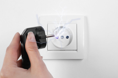 Image of Woman receiving electric shock while unplugging, closeup