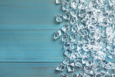 Pile of crushed ice on turquoise wooden table, top view. Space for text