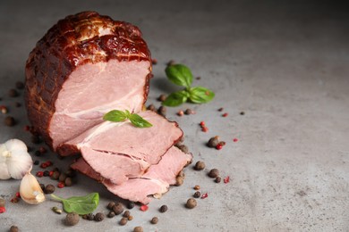 Photo of Delicious ham with spices, garlic and basil on grey table, space for text