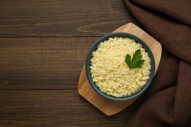 Photo of Tasty couscous with parsley on wooden table, top view. Space for text