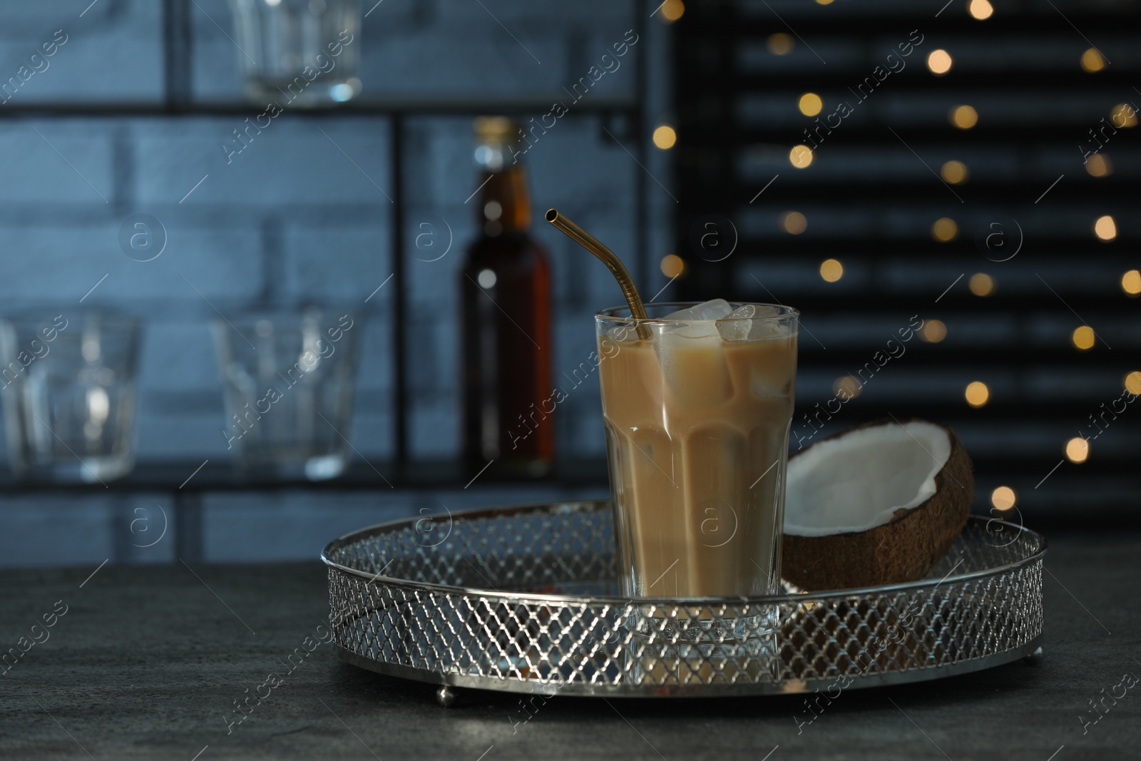 Photo of Glass of iced coffee and coconut on grey table against blurred lights. Space for text