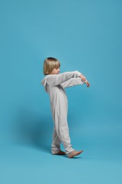 Boy in pajamas sleepwalking on light blue background