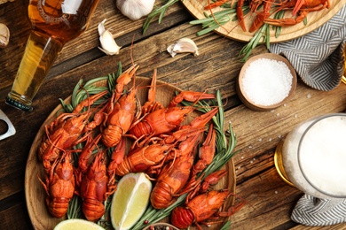 Photo of Flat lay composition with delicious red boiled crayfishes and beer on wooden table