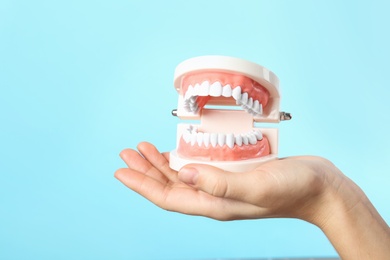 Photo of Woman holding educational model of oral cavity with teeth on color background. Space for text