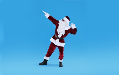 Photo of Full length portrait of Santa Claus with sunglasses on light blue background