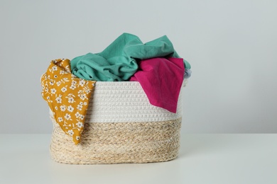 Photo of Wicker laundry basket with different clothes on light background