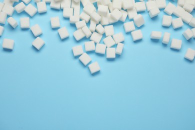 Photo of White sugar cubes on light blue background, flat lay. Space for text