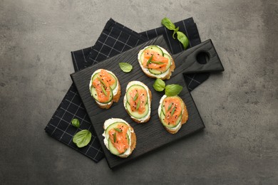 Photo of Tasty canapes with salmon, cucumber and cream cheese on grey table, top view