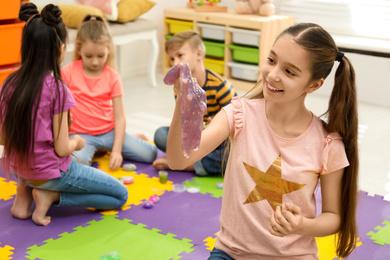 Photo of Preteen girl playing with slime in room