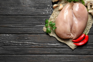 Photo of Flat lay composition with raw chicken breasts and space for text on wooden background
