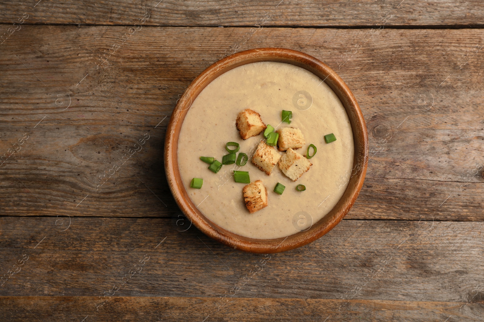 Photo of Bowl of fresh homemade mushroom soup on wooden background, top view