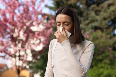 Photo of Woman with napkin suffering from seasonal allergy on spring day