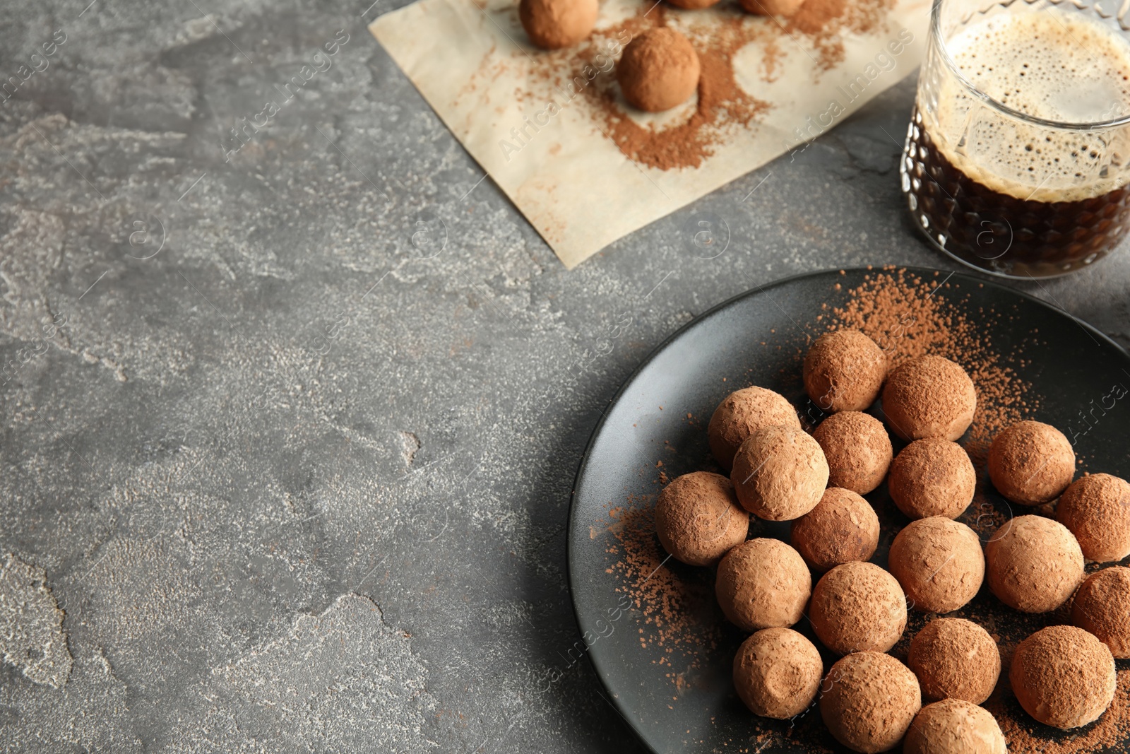 Photo of Plate with chocolate truffles on grey background, space for text