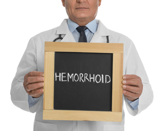 Photo of Doctor holding blackboard with word HEMORRHOID on white background, closeup
