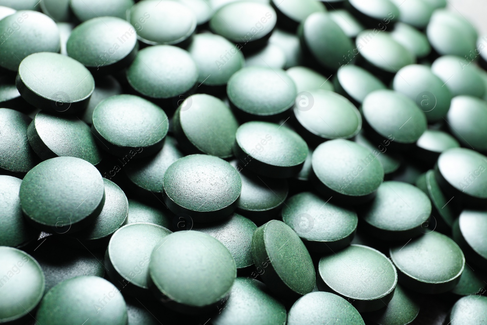 Photo of Green spirulina pills as background, closeup view