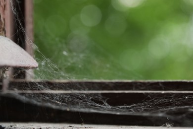 Photo of Cobweb on old wooden window frame indoors, closeup