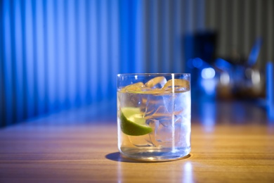 Photo of Glass of delicious cocktail with vodka on wooden counter in bar