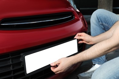 Photo of Man installing vehicle registration plate outdoors, closeup. Mockup for design