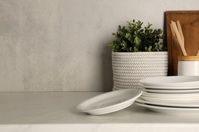 Photo of Set of clean plates on light table near wall, space for text