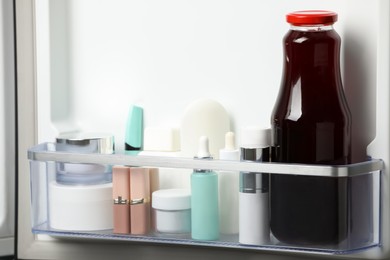Photo of Different cosmetic products on shelf in refrigerator
