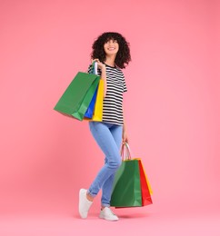 Photo of Happy young woman with shopping bags on pink background