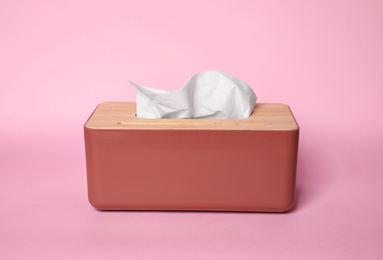 Photo of Holder with paper tissues on pink background