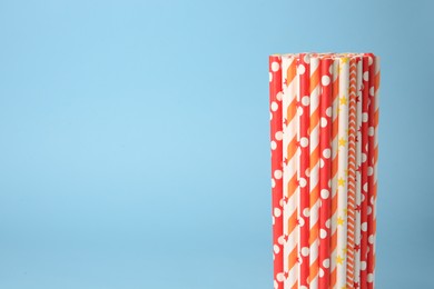 Photo of Colorful paper drinking straws on light blue background. Space for text