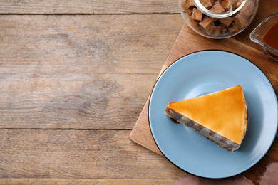 Photo of Slice of delicious cake with caramel sauce on wooden table, flat lay. Space for text