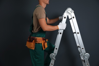 Photo of Professional constructor climbing ladder on black  background, closeup