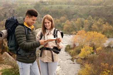 Photo of Couple of travelers with backpacks and map planning trip in mountains. Autumn vacation