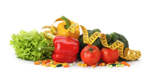 Weight loss pills, different vegetables and measuring tape on white background