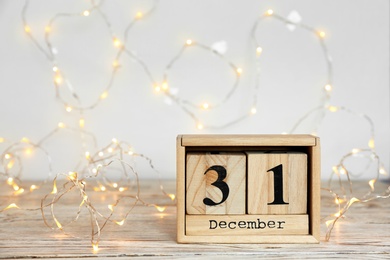 Photo of Wooden block calendar and electric garland on table. Christmas countdown